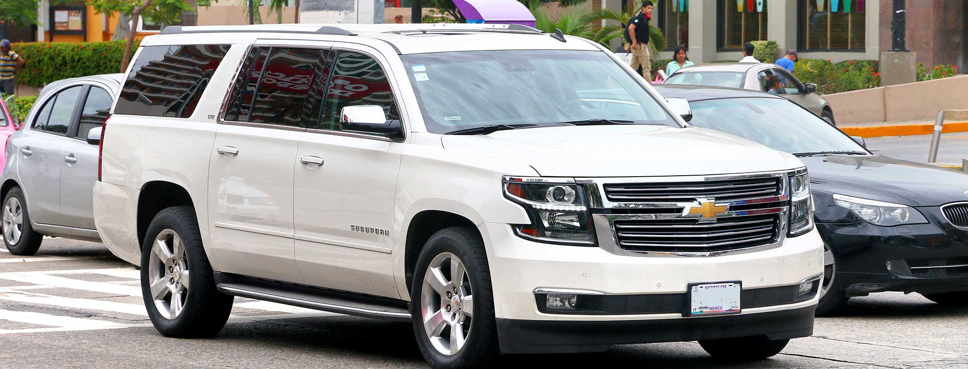 A white Chevy Suburban in a city steet