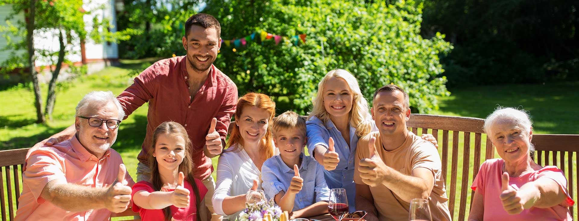 A family eating at a table and giving the camera a thumbs up