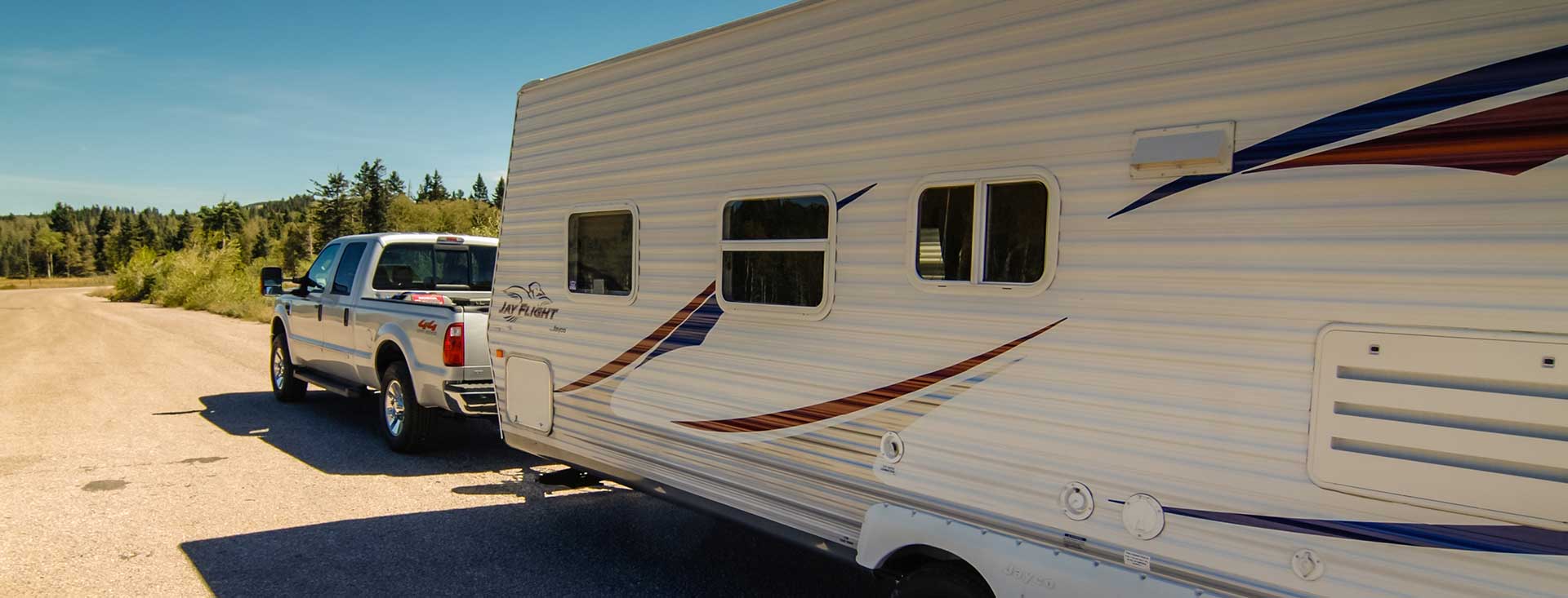 An RV being pulled by a silver truck